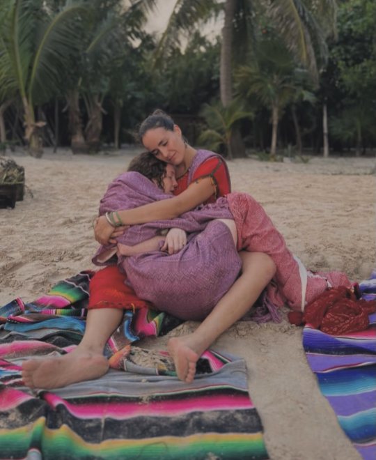 María abrazando a una mujer en la playa